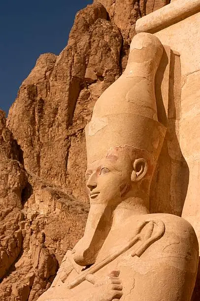 Close up view of a statue of Queen Hatshepsut. Valley of the Queens, with the mountains of Djeser-Djeseru in the background.
