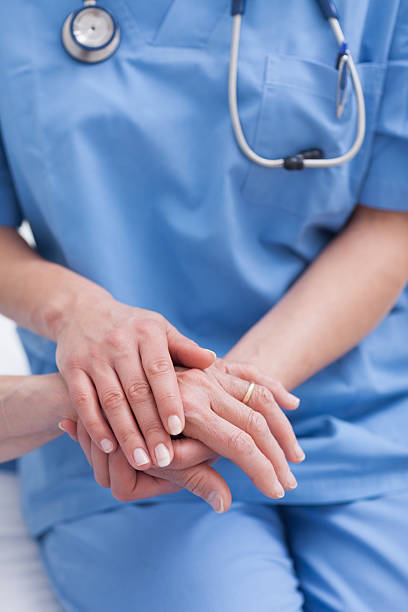 An Asian female medical practitioner reassuring a senior patient at a rehabilitation center.