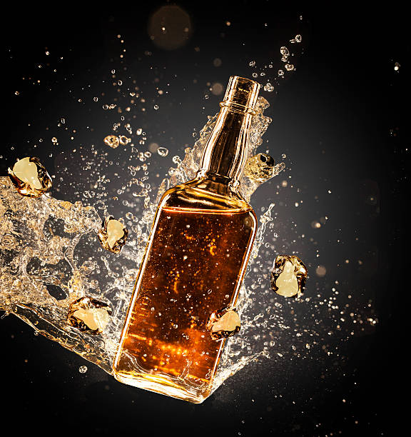Isolated shot of whiskey splashing out of bottle on black background