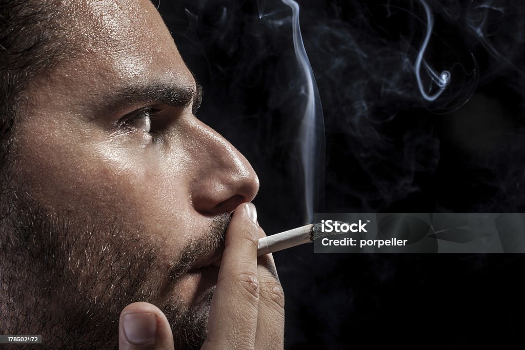 Worried and smoking a man smoking a cigarette on a black background Addict Stock Photo