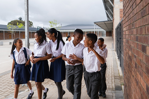 A large group of black school children from a rural school in Cape Town walking to their classroom. Children excited to start the school day.