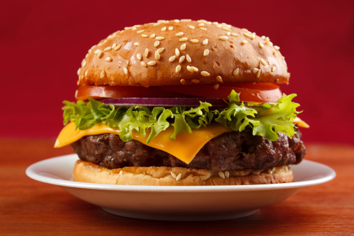 Homemade grilled hamburger on plate with red background