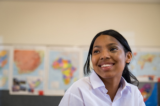 Portrait of a young African schoolgirl with a birthmark listening to her teacher