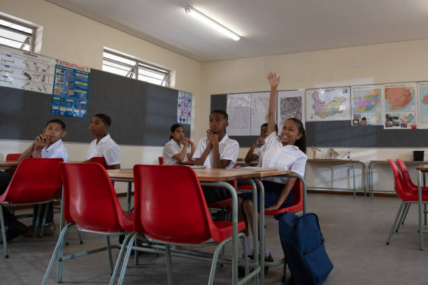 istock Young girl in class raises her hand to answer the teachers question 1785042867