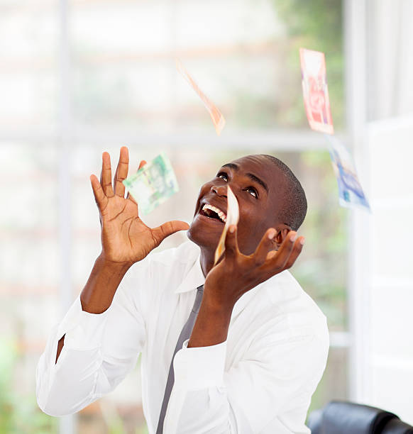 businessman catching money falling from above