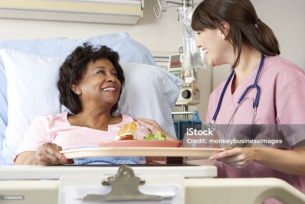 Nurse Serving Senior Patient Meal In Hospital Bed Female Nurse Serving Senior Female Patient Meal In Hospital Bed Hospital Stock Photo