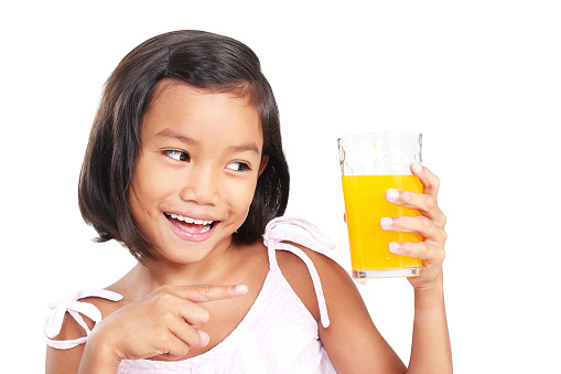 Happy girl pointing to a glass of orange juice.Isolated in white background.