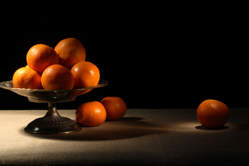 Vintage brass fruit bowl with tangerines on canvas surface
