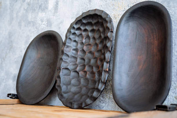 Kitchen utensils made of natural material. A close shot of a set of wooden plates of dark color. One of the plates has a textured surface with notations. Cutting wood and creating dishes, toys, souvenirs from it. The other two have a flat bottom. High quality photo utensilios de cocina fabricados en material natural. un primer plano de un conjunto de placas de madera de color oscuro. una de las placas tiene una superficie texturizada con anotaciones. cortar madera y crear platos, juguetes, recuerdos a partir de ella.