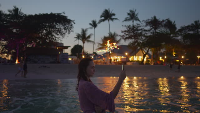 Woman with smartphone on beach vacation after sunset