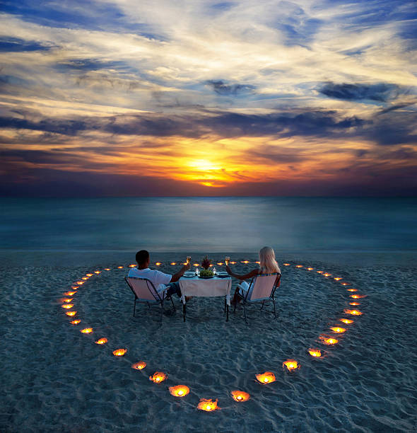 joven pareja compartir una cena romántica en la playa - luna de miel fotografías e imágenes de stock