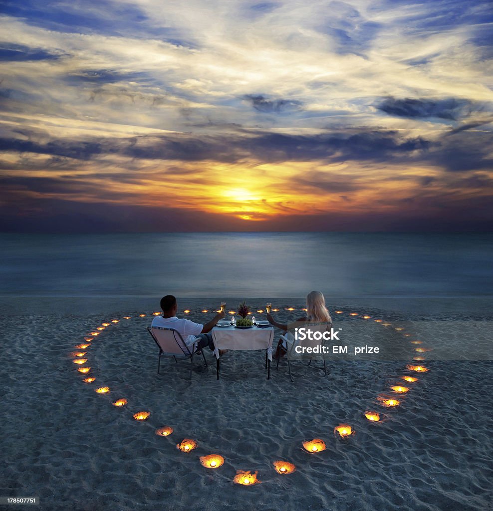 young couple share a romantic dinner on the beach young couple share a romantic dinner with candles heart on the sea sand beach Beach Stock Photo