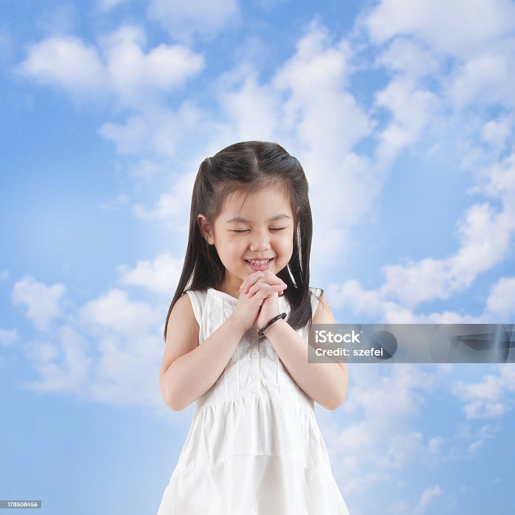 Praying East Asian girl making a wish with smiling, blue sky as background Girls Stock Photo