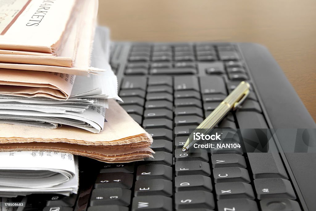 Newspapers on the Keyboard Pile of Newspapers on the Computer Keyboard close up Black Color Stock Photo