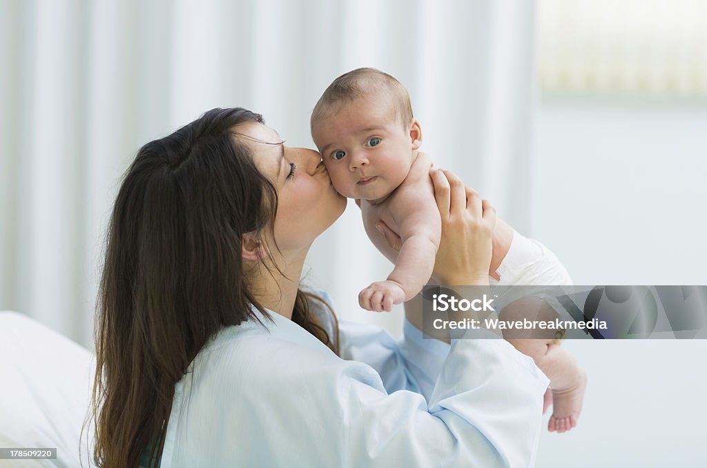 Mother kissing a baby boy in diaper Mother kissing a baby boy in diaper in a hospital room 30-39 Years Stock Photo