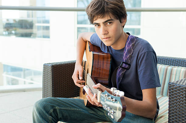 istock Brooding cute teenage boy playing Acoustic Guitar 178509268