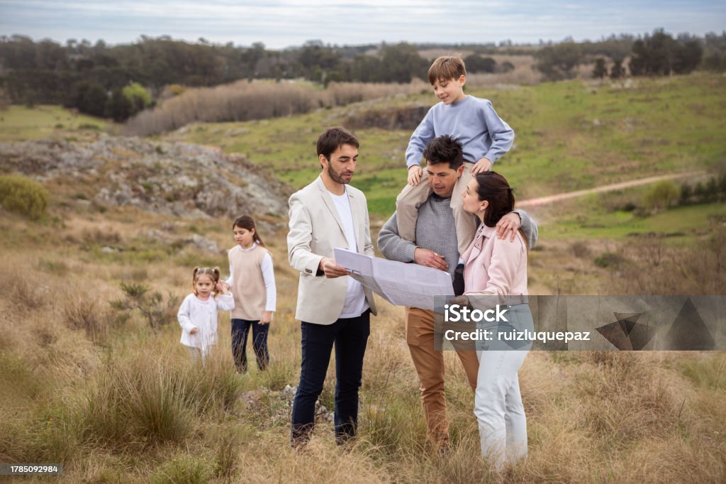 Real estate agent showing family allotment to build their new home Real estate agent showing family allotment to build their new home - Buenos Aires - Argentina 10-11 Years Stock Photo