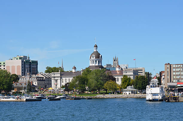 City Of Kingston Ontario Canada from the Water This photo shows City Hall in the City of Kingston Ontario Canada from the water. It shows the trees and fountain in Confederation Park in front of the domed City Hall building. The dome also has a clock and bell tower. A marina with boats is in front of the park also. A large tour boat sits waiting for tourists to tour the Thousand Islands. Kingston is on Lake Ontario where the St. Lawrence and Rideau Rivers meet. kingston harbour stock pictures, royalty-free photos & images