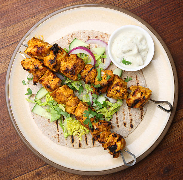 Two kebabs of Indian chicken tikka "Indian chicken tikka kebabs with chapatti, salad and raita." chicken skewer stock pictures, royalty-free photos & images