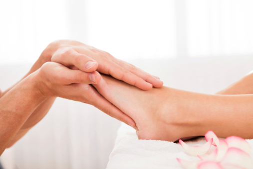 Massage therapist massaging a woman's feet at a beauty spa