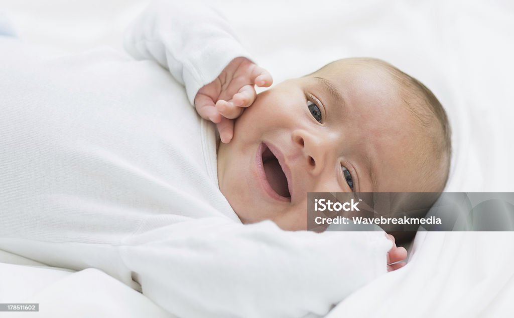 Nuovo NATO bambino sorridente sdraiato/a su un lettino - Foto stock royalty-free di Accudire