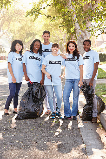 une équipe de volontaires soulever litière dans la banlieue de street - bag garbage bag plastic black photos et images de collection