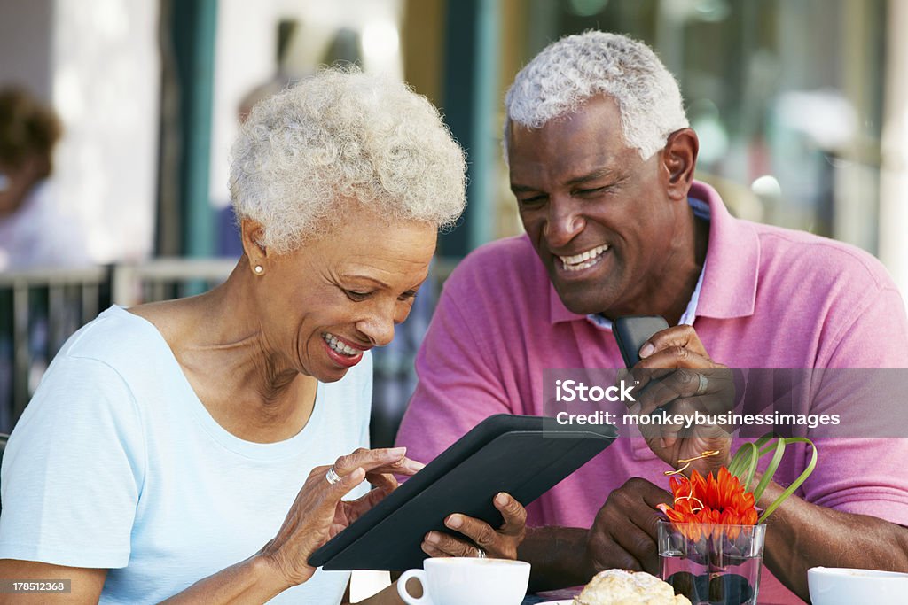 Senior Couple Using Tablet Computer At Outdoor Cafe Senior Couple Using Tablet Computer At Outdoor Cafe Smiling Senior Adult Stock Photo