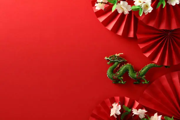 Photo of Dragon with Sakura and Folding Paper Fans on Red Background - Chinese New Year 2024 Celebration