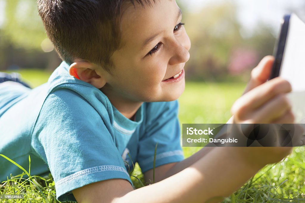 Little boy using digital tablet Little boy lying on the grass and using digital tablet Child Stock Photo