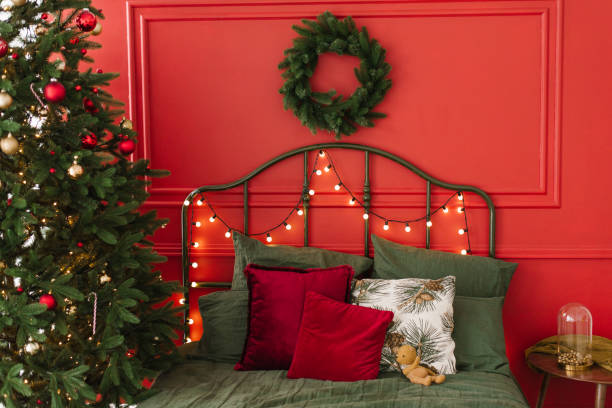 istock Classic bedroom interior with a Christmas tree with lights on a red wall background 1785143094