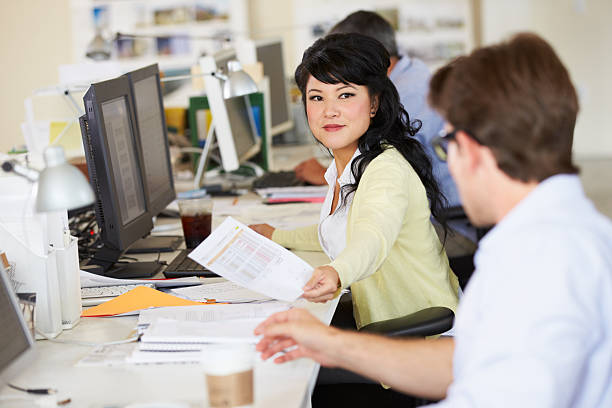 istock Woman working at a table with coworkers in busy office 178515006