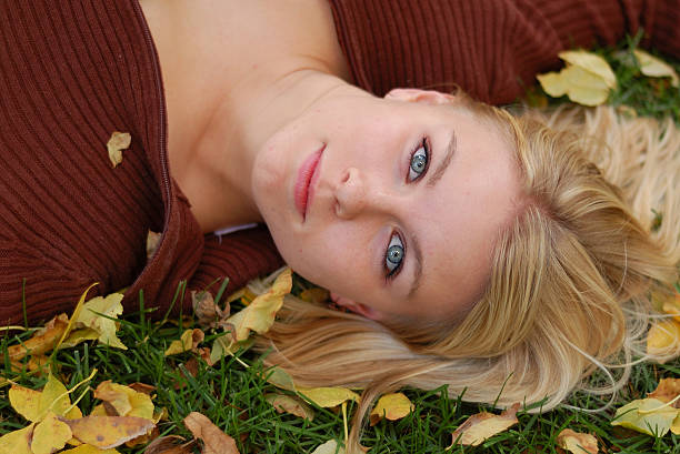 Beautiful woman lying on bed of Autumn leaves. stock photo