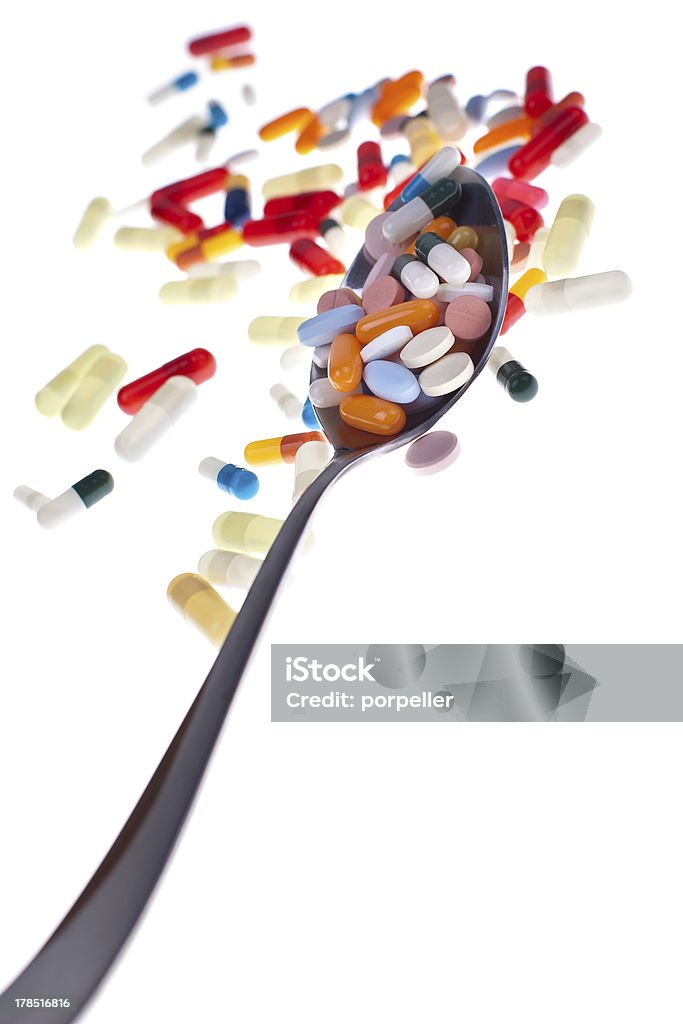 Spoon-o-meds A lot of colored pills and tabs with a spoon over a white background Addiction Stock Photo