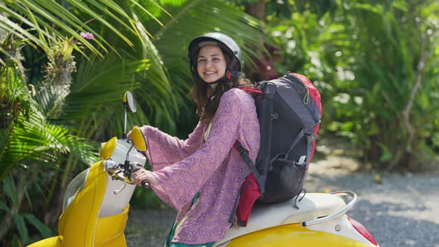 Woman backpacker traveling in tropics on scooter