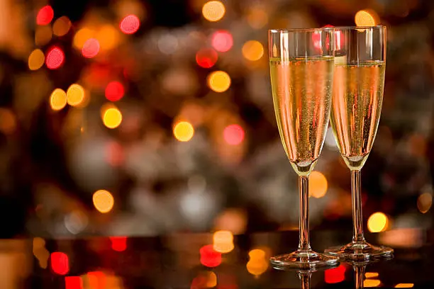 photo of two champagner glasses on glass table with bokeh background