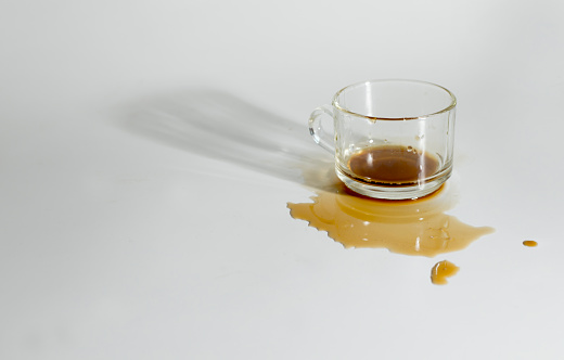 The coffee from the glass is sloppy, on the white background.