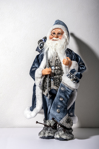 Santa Claus toy figure on white shelf on background of white wall.