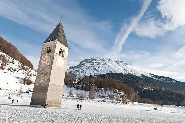 "Tourists walking on the frozen lake Resia, on a sunny winter day."