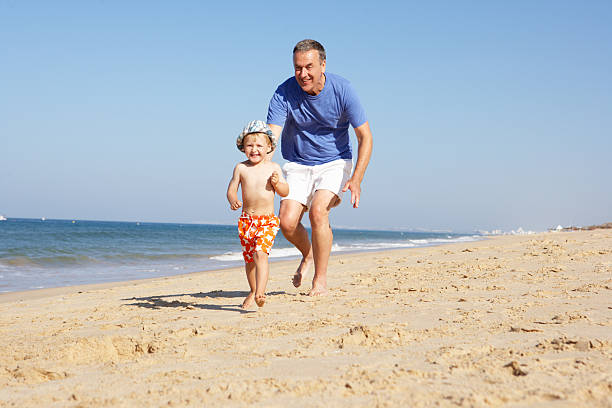 Grandfather with grandson running along the beach happily