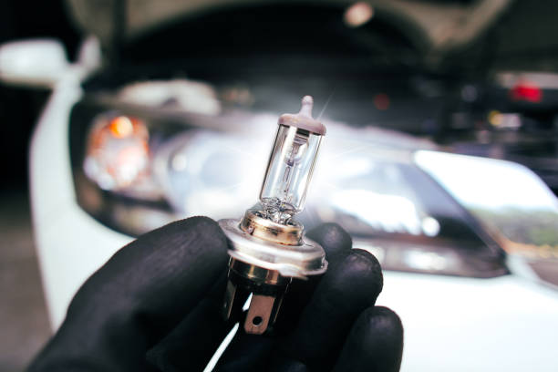 istock Car halogen bulb in auto mechanic hand with a car blurred background , H4 type 1785220501