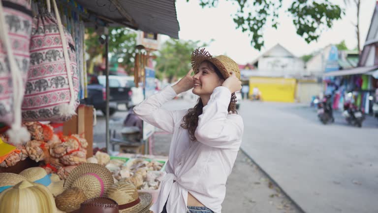 Woman buying hat in souvenir shop in Thailand