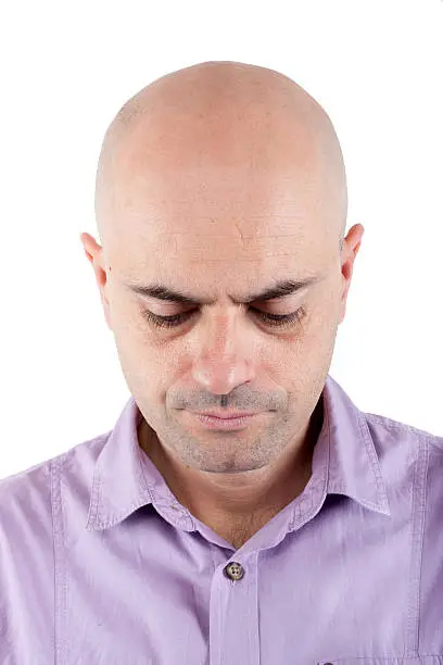 Photo of Worried bald  man looking down.