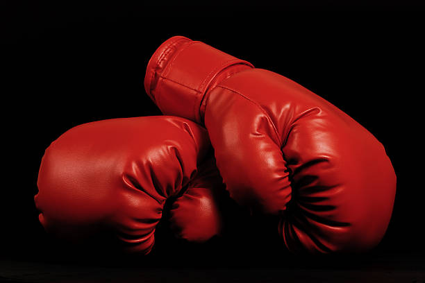 Vintage boxing gloves emerging from black background stock photo