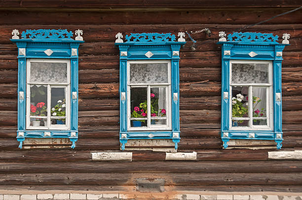 istock Beautiful blue fretted window cases on brown log cabin wall 178524622