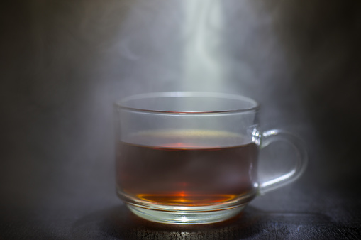 Coffee in a glass with smoke and a black background