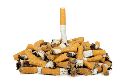 quit smoking concept with whole cigarette among cigarette butts