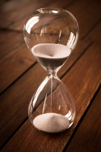 istock Hourglass containing white sand on a rustic wooden board 1785271151