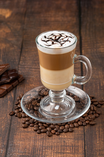 Multilayer coffee latte in glass cup on wooden table