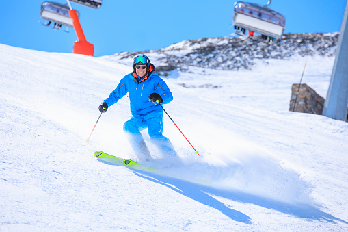 Active lifestyle, Vital senior men snow skier skiing, enjoying on sunny ski resorts. Skiing carving at high speed.  Alps  ski area. Ski resort Livigno. italy, Europe.