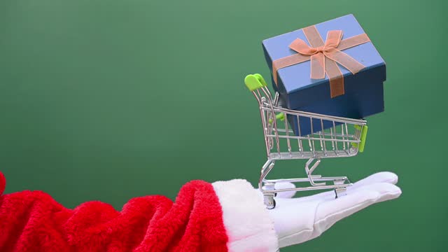 Santa Claus lifting up a shopping cart with a gift box